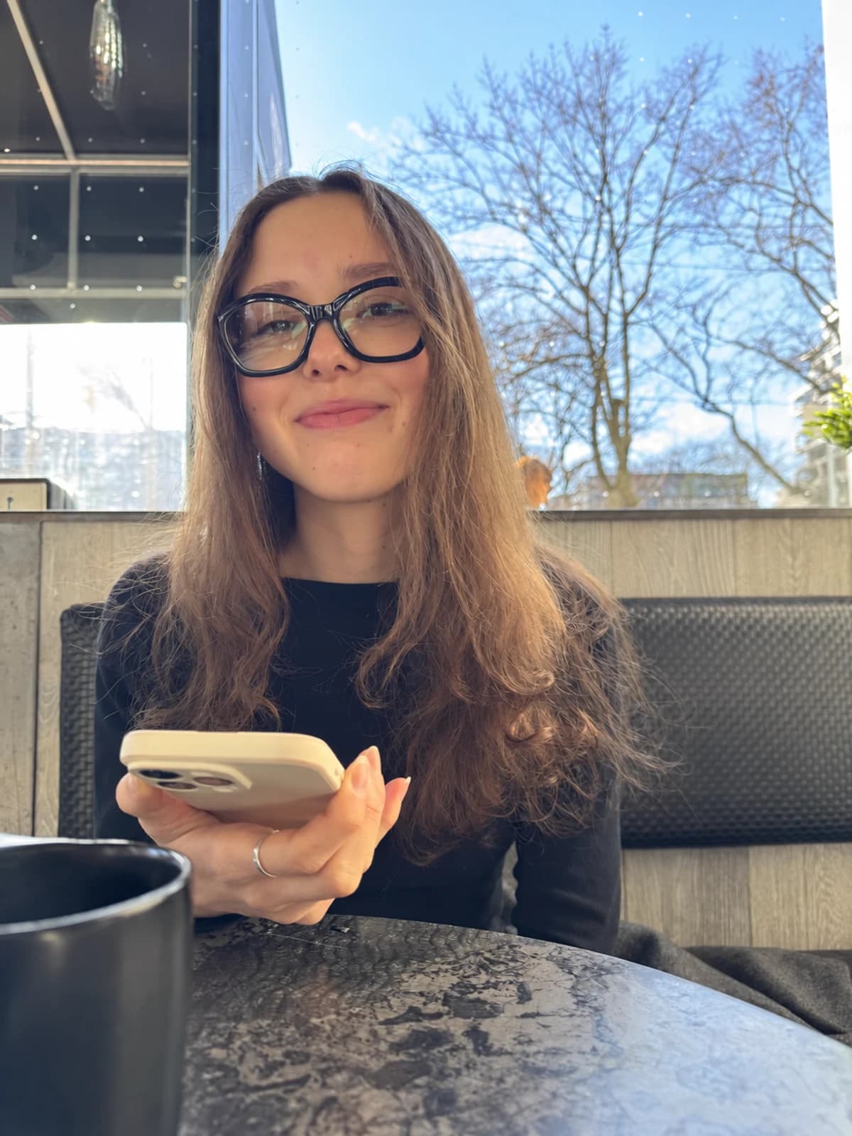 Tanya smiling at a table in a sunlit café